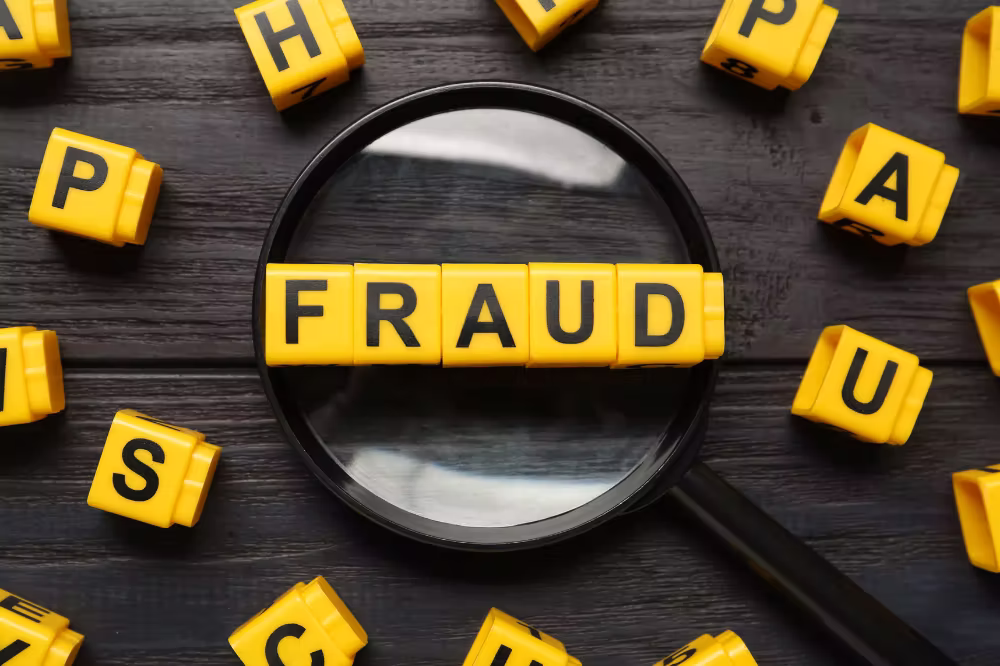 popular-scams-to-look-out-for Several letter blocks scattered, with a magnifying glass showing a row of them that say, "FRAUD"